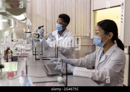 Uno dei chimici con il topo bianco che esamina il nuovo vaccino in laboratorio Foto Stock