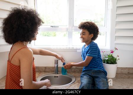 Madre che aiuta il figlio a lavarsi le mani a casa Foto Stock