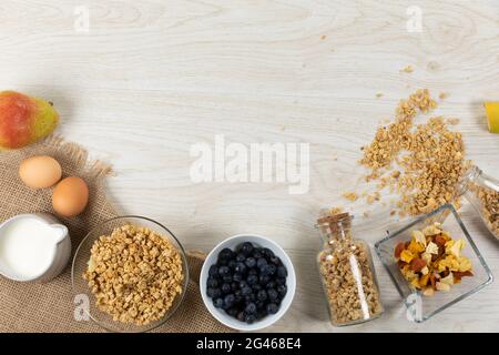 Vista di una varietà di noci e muesli, ciotole di frutta secca e uova su superficie di legno Foto Stock