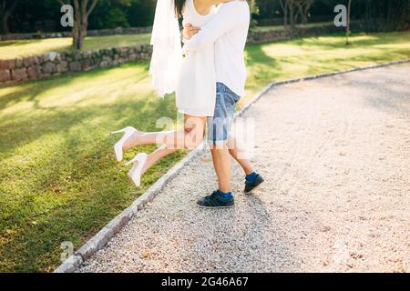 Il govern sollevato la sposa nelle sue braccia. Gambe di close-up. I matrimoni Foto Stock