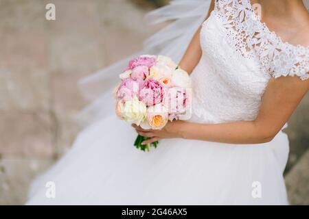 Wedding rose e peonie nelle mani della sposa. Nozze in Foto Stock