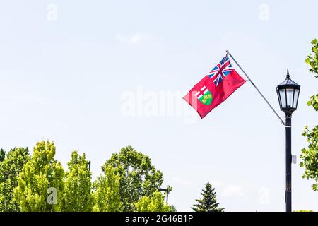 Bandiera provinciale dell'Ontario che vola nel vento. Sul palo della bandiera attaccato al lampione nero antico. Sfondo cielo, spazio per il testo. Foto Stock