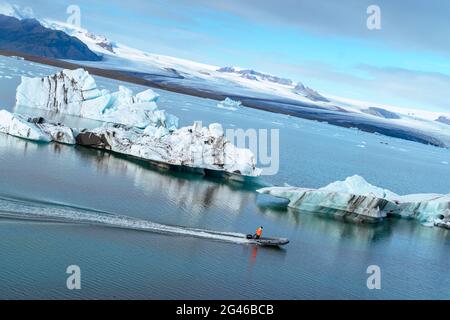 Un uomo che naviga attraverso le file di iceberg su un motoscafo a Jokulsarlon, Islanda Foto Stock