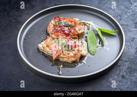 Saltimbocca alla Romana di maiale fritto in stile moderno con prosciutto di Parma e foglie di salvia offerti da vicino in un Nord Foto Stock