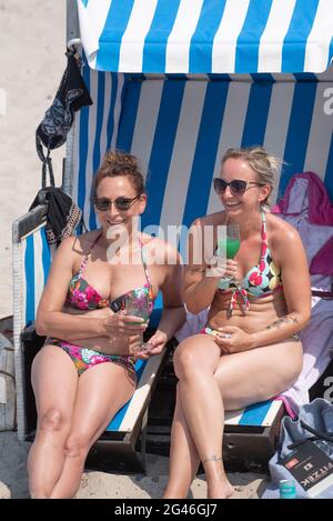 Rostock, Germania. 19 giugno 2021. A metà estate la spiaggia di Warnemünde Antje e Nancy si trovano su una sedia da spiaggia. Nel fine settimana del 19.06.20021 iniziano le vacanze estive a Meclemburgo-Vorpommern. Credit: Frank Hormann/dpa/Alamy Live News Foto Stock