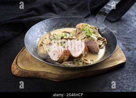 Tradizionale barbecue medaglioni iberici di filetto di maiale in salsa di crema con funghi ed erbe offerte da vicino in un rustico adirug Foto Stock