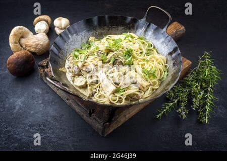 Spaghetti ai funghi porcini con funghi in salsa di panna offerti da vicino in una rustica padella di ferro battuto Foto Stock