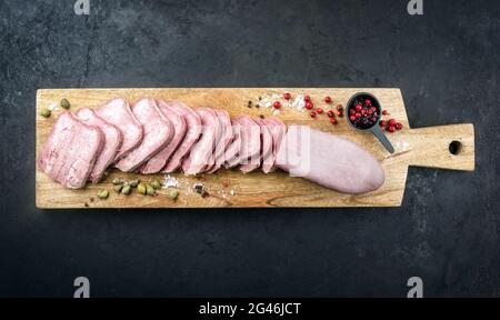 Lingua tradizionale di manzo cotta con mirtilli rossi e pistacchi offerti come vista dall'alto su una tavola di legno di design Foto Stock