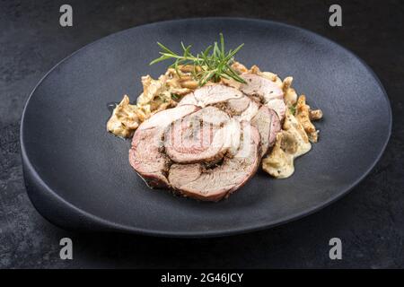 Tradizionale arrosto di agnello barbecue francese affettato con chanterelles in salsa di crema offerto da primo piano su un piatto di design in ghisa Foto Stock