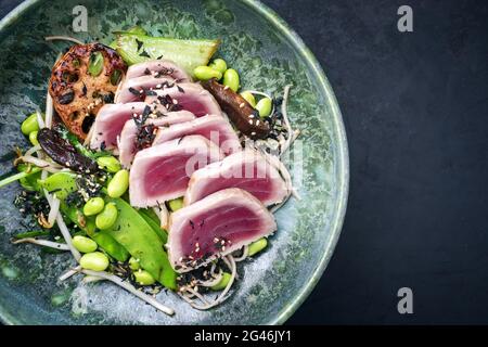 Stile moderno tradizionale giapponese gourmet pesce di tonno scottato bistecca tataki con soba noodle e verdure fritte in tegame come a Foto Stock