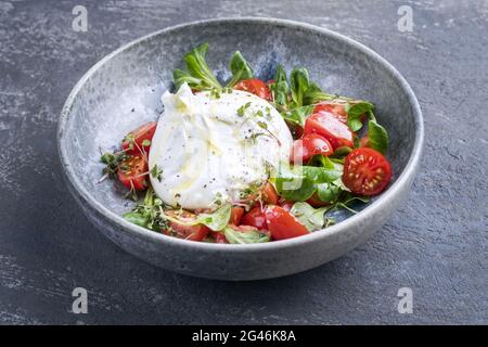 Burrata italiana di stile moderno a base di mozzarella e panna servita con insalata di pomodoro e mais in ceramica Foto Stock