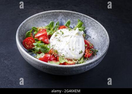 Moderno stile Italiano Puglia formaggio di mucca Burrata a base di mozzarella e panna servito con insalata di pomodoro e mais in ceramica Foto Stock