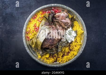 Shuwa agnello Omani cotto lentamente rivestito in strofinamento di spezie e avvolto in foglie di banana servito con riso e yogurt come vista dall'alto su a. Foto Stock