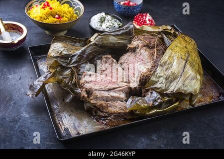 Shuwa agnello Omani cotto lentamente rivestito in strofinamento di spezie e avvolto in foglie di banana servito con riso e yogurt come primo piano su a. Foto Stock