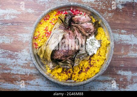 Shuwa agnello Omani cotto lentamente rivestito in strofinamento di spezie e avvolto in foglie di banana servito con riso e yogurt come vista dall'alto su a. Foto Stock