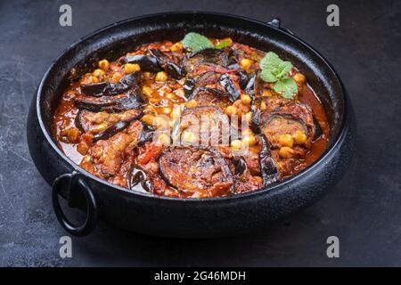 In stile moderno, il maghmour vegetariano libanese di stufato di melanzane cucinato lentamente viene servito con ceci da vicino in una pentola di design Foto Stock