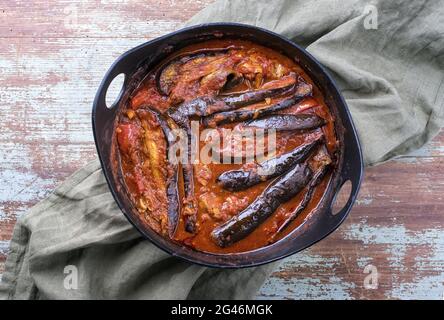 In stile moderno, lo stufato di melanzane di agnello persiano cucinato lentamente khoresh bademjan è servito da primo piano in un vaso di design su una tavola di legno con c. Foto Stock