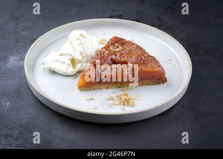 Tatin di tarte francese tradizionale con mele e gelato offerto come primo piano su un moderno piatto di design nordico con backgro rustico Foto Stock