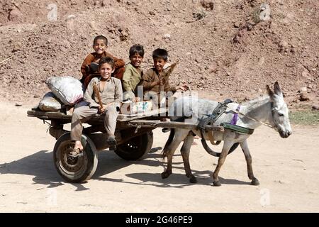 Islamabad, Pakistan. 19 giugno 2021. I bambini afghani rifugiati si possono guidare su un carro di asini in una baraccopoli alla vigilia della Giornata Mondiale dei rifugiati, alla periferia di Islamabad, Pakistan, il 19 giugno 2021. Secondo l’Alto Commissariato delle Nazioni Unite per i rifugiati (UNHCR), il Pakistan ospita attualmente più di 1.4 milioni di rifugiati afghani registrati che sono stati costretti a fuggire dalle loro case. Credit: Ahmad Kamal/Xinhua/Alamy Live News Foto Stock