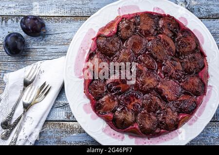 Tarte aux prugne tradizionali francesi con prugne dolci e vaniglia offerto come vista dall'alto su un piatto di design classico con legno rustico Foto Stock