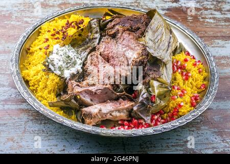 Shuwa agnello Omani cotto lentamente rivestito in strofinamento di spezie e avvolto in foglie di banana servito con riso e yogurt come primo piano su a. Foto Stock