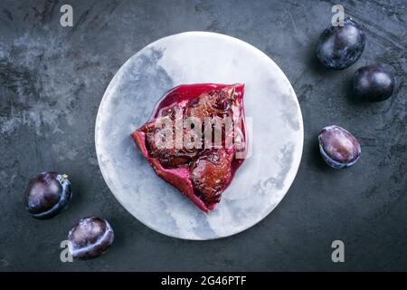 Tarte aux prunes francese di stile moderno con prugne dolci e vaniglia offerti come vista dall'alto su uno spazio di disegno copia piastra Foto Stock