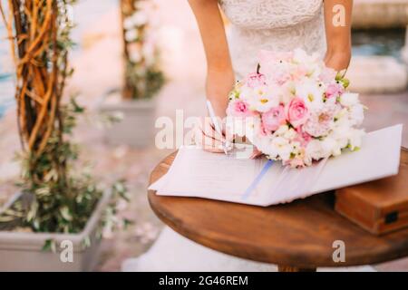 Sposi mettere le loro firme nell'atto di registrazione di un matrimonio Foto Stock