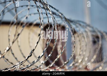 Spirali di filo spinato su una recinzione di cemento. Un simbolo di incarcerazione e di mancanza di libertà. Foto Stock