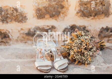 Scarpe di nozze di una sposa su un sfondo di pietra e di un bianco bouquet nuziale Foto Stock