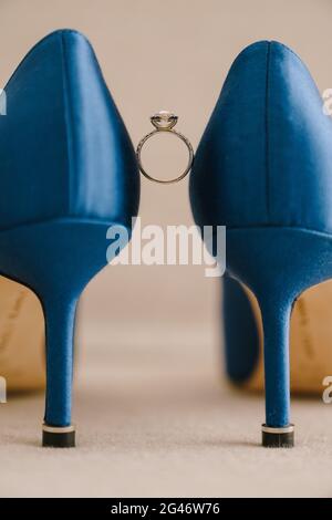 L'anello di fidanzamento della sposa con gemme tra scarpe blu con tacco alto. Foto Stock