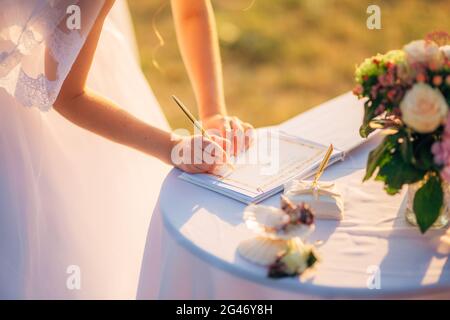 Sposi mettere le loro firme nell'atto di registrazione di un matrimonio Foto Stock