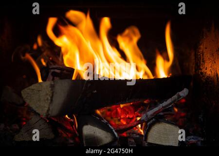 Primo piano di fiamme e legna da ardere in un camino. Foto Stock