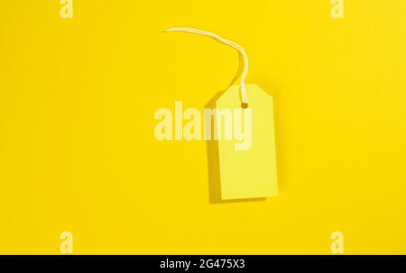 Cartellino bianco rettangolare in carta giallo con corda bianca su sfondo giallo Foto Stock