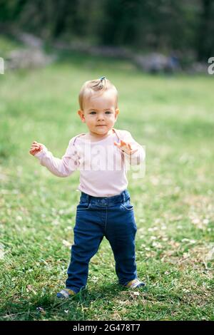 Bambina divertente che cammina in un prato verde Foto Stock