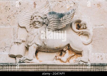 Un bassorilievo sulla parete raffigurante un leone mitico con le ali e un libro nelle zampe. Foto Stock