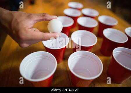 Mano tagliata dell'uomo che gioca a beer pong Foto Stock