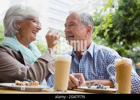 Donna anziana che alimenta la crostata all'uomo a cafÃƒÂ© Foto Stock