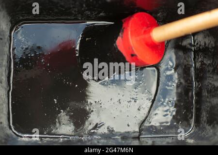 Pennello in vernice nera. Spazzolare in un contenitore con vernice impermeabile. Uno strumento per la colorazione della superficie. Vernice spessa in un vaso. Foto Stock