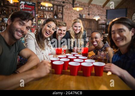 Ritratto di amici sorridenti intorno a tazze usa e getta sul tavolo Foto Stock