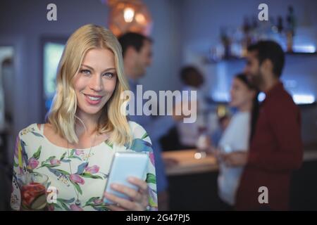Bella donna utilizzando il telefono cellulare presso il bar ristorante Foto Stock