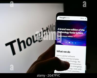 Persona che tiene il cellulare con la pagina web della società americana di software ThoughtWorks Inc. Sullo schermo davanti al logo. Mettere a fuoco il centro del display del telefono. Foto Stock