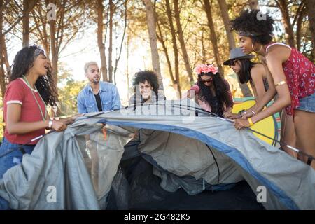 Felici i giovani amici che si accusano la tenda Foto Stock