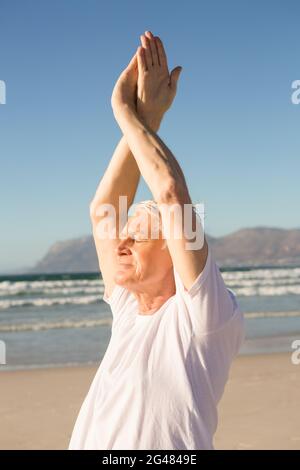 L'uomo anziano con gli occhi chiusi gli esercizi in spiaggia Foto Stock