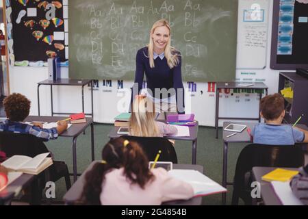 Insegnante aiutando schoolkids con i loro compiti in classe Foto Stock