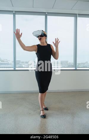 Executive femmina utilizzando la realtà virtuale auricolare in carica Foto Stock