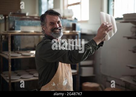 Ritratto del vasaio maschio che controlla la ciotola di ceramica Foto Stock