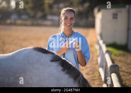 Ritratto di una siringa femmina sorridente che tiene il veterinario Foto Stock