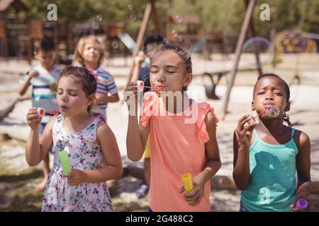 Schoolkids che gioca con la bacchetta a bolle Foto Stock