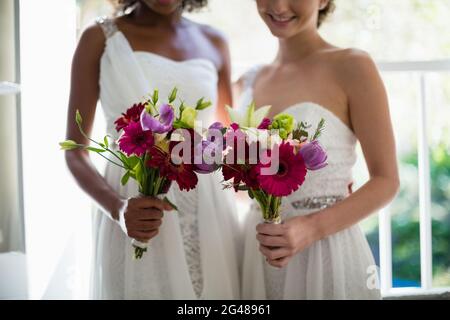 Sposa e bridesmaid in piedi con bouquet Foto Stock