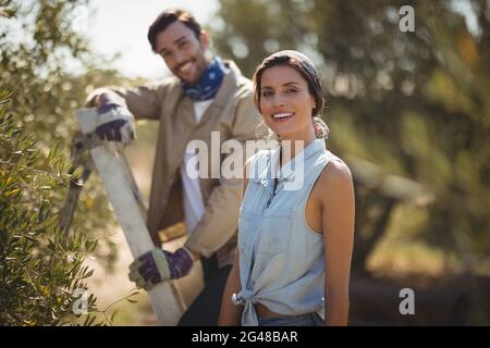 Felice giovane coppia in piedi da alberi presso l'olivicoltura Foto Stock